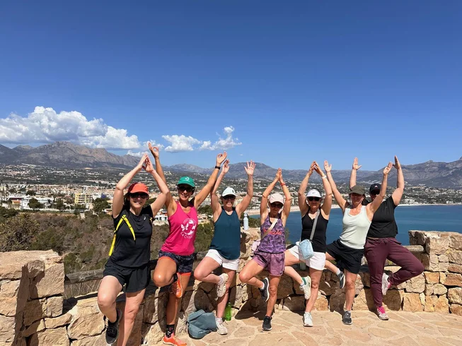 Retreat participants practising a standing yoga pose overlooking the Costa Blanca coastline